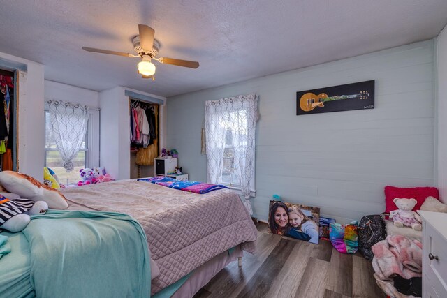 bedroom with ceiling fan, hardwood / wood-style floors, multiple windows, and a textured ceiling