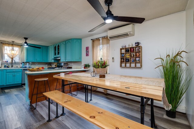 kitchen featuring a wealth of natural light, sink, kitchen peninsula, blue cabinetry, and a wall unit AC