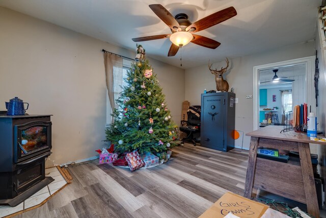 misc room featuring light hardwood / wood-style floors, ceiling fan, and a wood stove