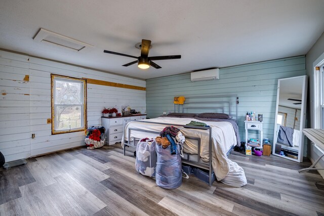 bedroom with hardwood / wood-style floors, a wall mounted air conditioner, and ceiling fan