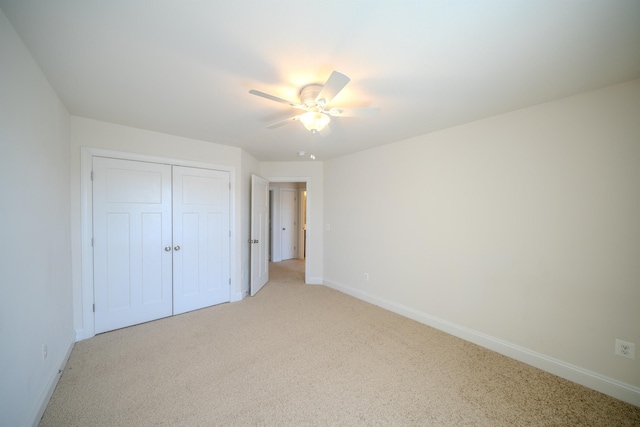 unfurnished bedroom featuring light colored carpet, ceiling fan, and a closet