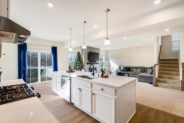 kitchen with sink, dishwasher, white cabinetry, an island with sink, and decorative light fixtures