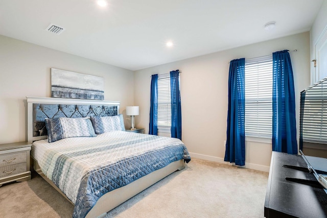 bedroom with multiple windows and light colored carpet