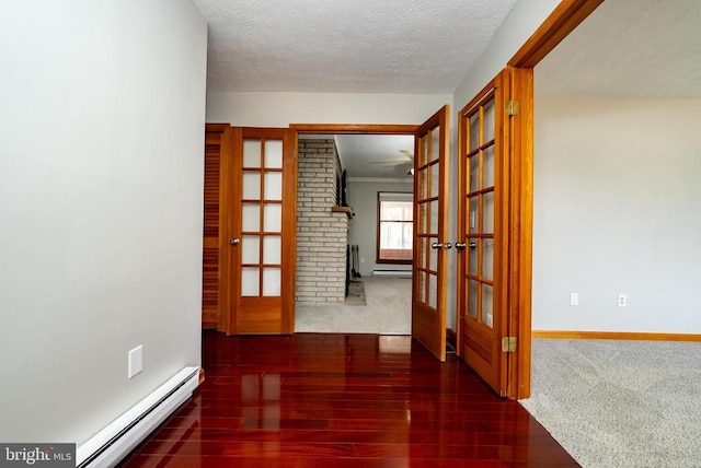 corridor featuring baseboards, a baseboard radiator, wood finished floors, a textured ceiling, and french doors