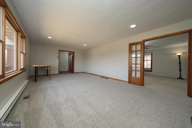 carpeted empty room with recessed lighting, a baseboard heating unit, a textured ceiling, and french doors