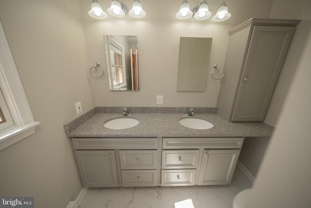 bathroom with marble finish floor, double vanity, and a sink