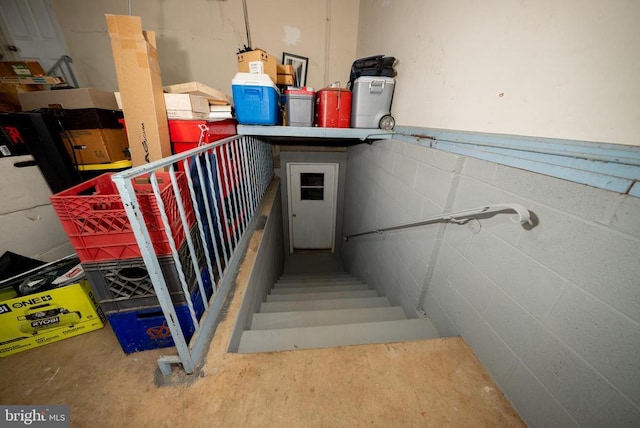 stairway featuring concrete block wall