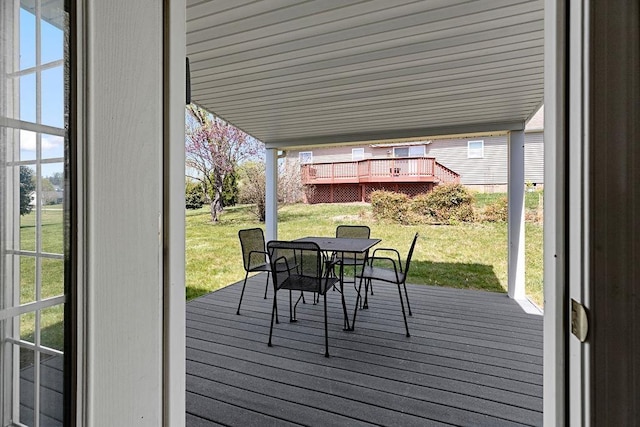 deck featuring outdoor dining area and a lawn
