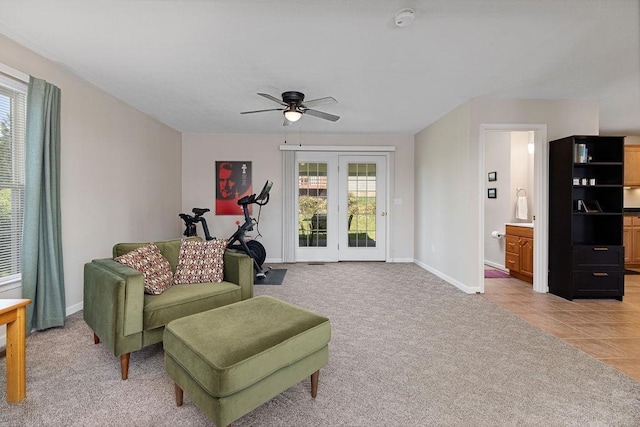 sitting room featuring light colored carpet, a wealth of natural light, a ceiling fan, and baseboards