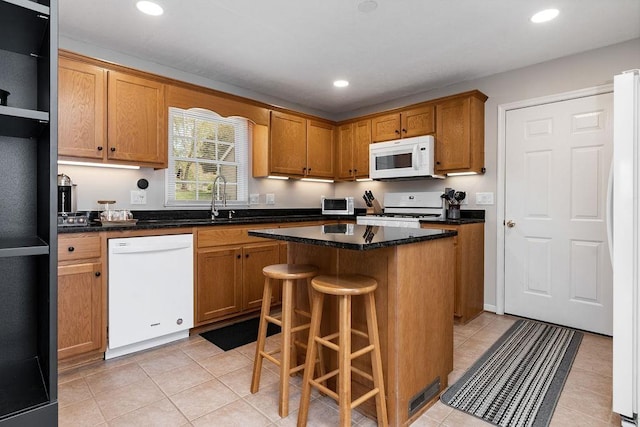 kitchen with recessed lighting, light tile patterned floors, a sink, white appliances, and a kitchen island