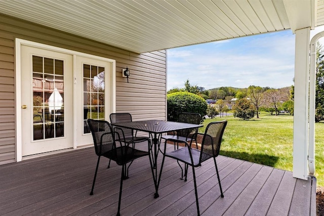wooden terrace with a lawn and outdoor dining area