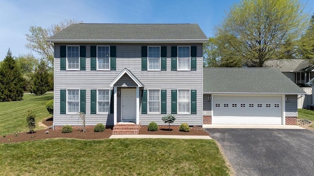 colonial inspired home featuring an attached garage, a front lawn, and driveway