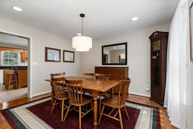 dining space featuring baseboards, wood finished floors, and recessed lighting