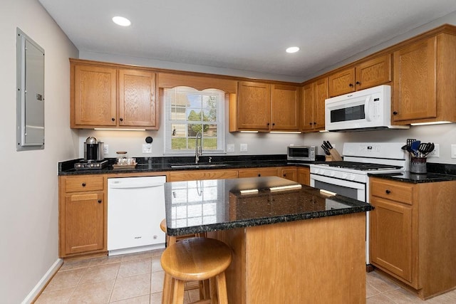 kitchen featuring dark stone counters, a sink, electric panel, white appliances, and light tile patterned floors