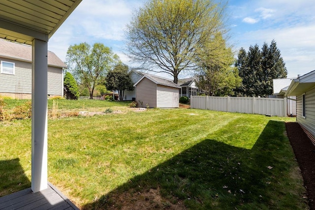 view of yard featuring a storage shed, an outbuilding, and fence