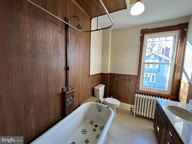 bathroom with vanity, a bathing tub, wallpapered walls, radiator heating unit, and wainscoting