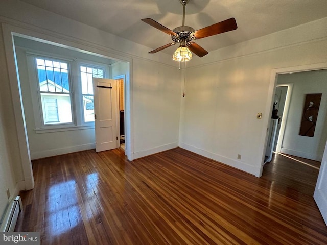 spare room with a baseboard radiator, baseboards, and dark wood finished floors