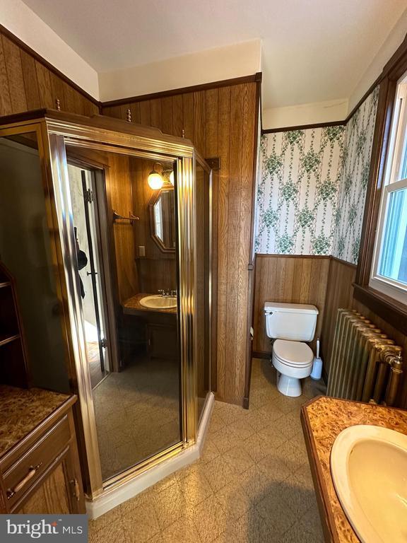 bathroom with vanity, radiator, wood walls, wainscoting, and tile patterned floors