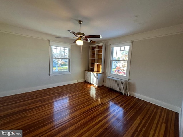 unfurnished room with baseboards, radiator, wood finished floors, and a ceiling fan