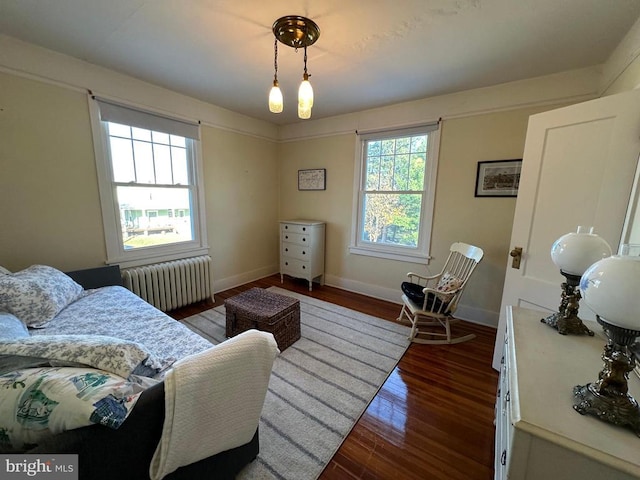 bedroom with radiator heating unit, wood finished floors, and baseboards