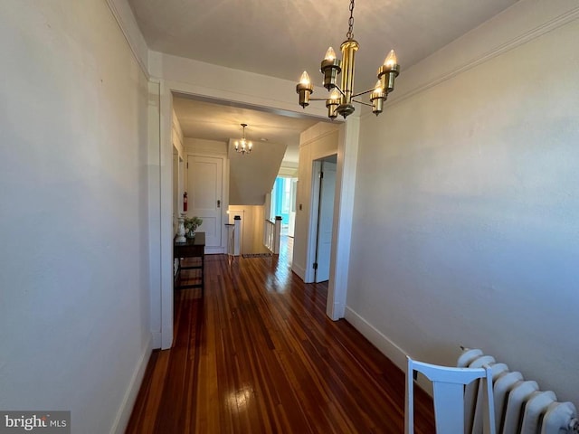 hall with radiator, baseboards, dark wood-type flooring, and an inviting chandelier