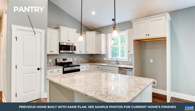 kitchen with pendant lighting, sink, white cabinetry, stainless steel appliances, and a kitchen island