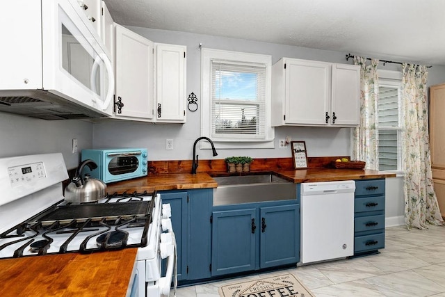 kitchen featuring a sink, white appliances, blue cabinetry, and wood counters