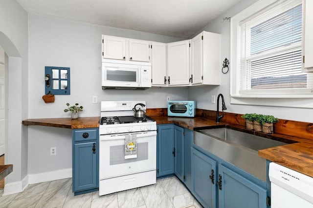 kitchen with white appliances, blue cabinetry, and butcher block counters