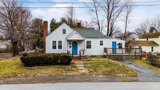 view of front of property featuring aphalt driveway, a wooden deck, and a chimney