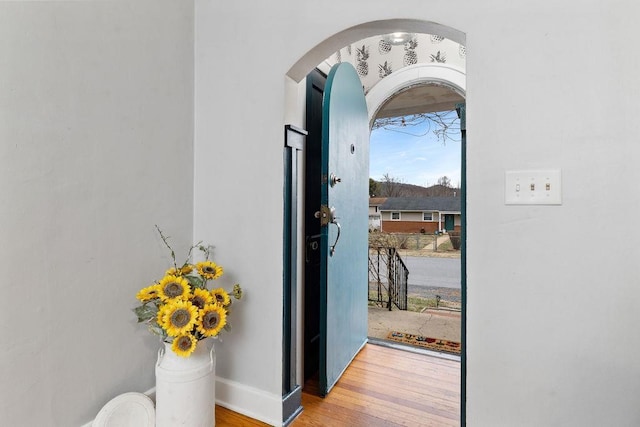 entryway with baseboards, arched walkways, and wood finished floors