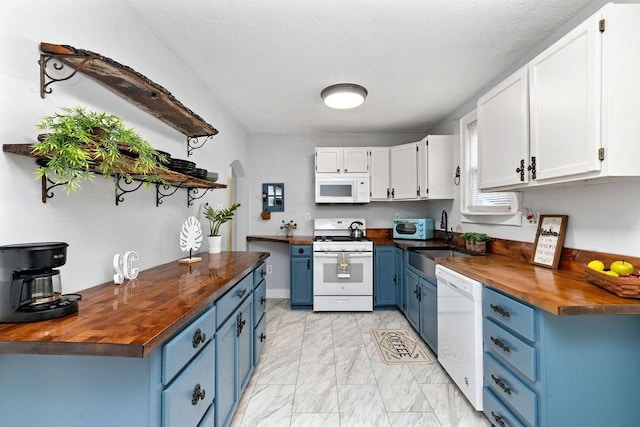 kitchen with white appliances, arched walkways, a sink, butcher block countertops, and blue cabinets