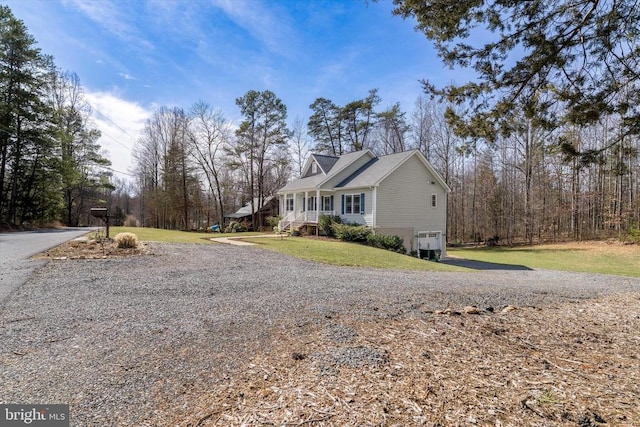 view of property exterior with a porch, a lawn, driveway, and an attached garage