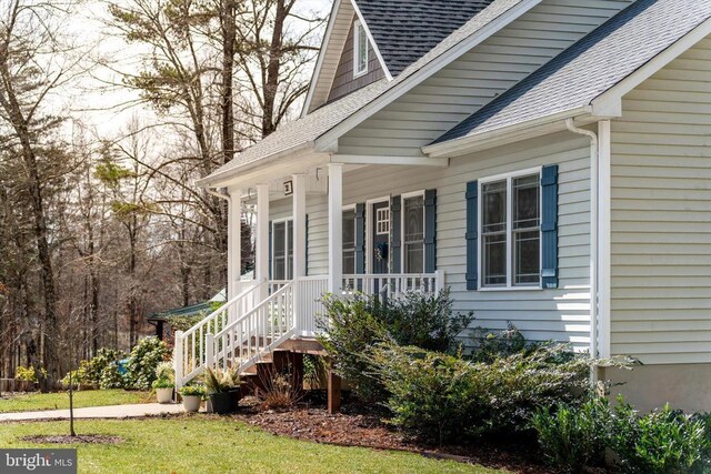 entrance to property featuring covered porch and roof with shingles