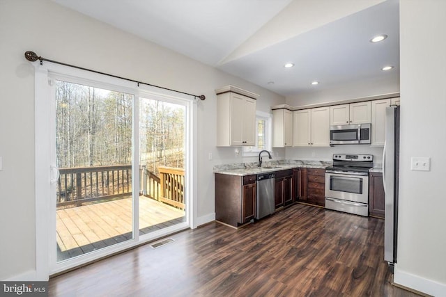 kitchen with light stone counters, recessed lighting, dark wood-style flooring, a sink, and stainless steel appliances