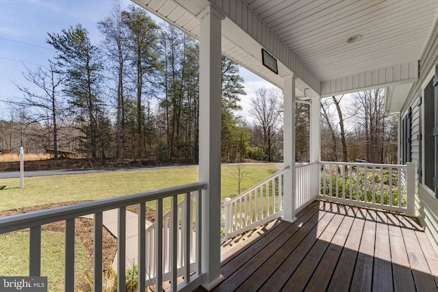 wooden terrace featuring a porch and a yard