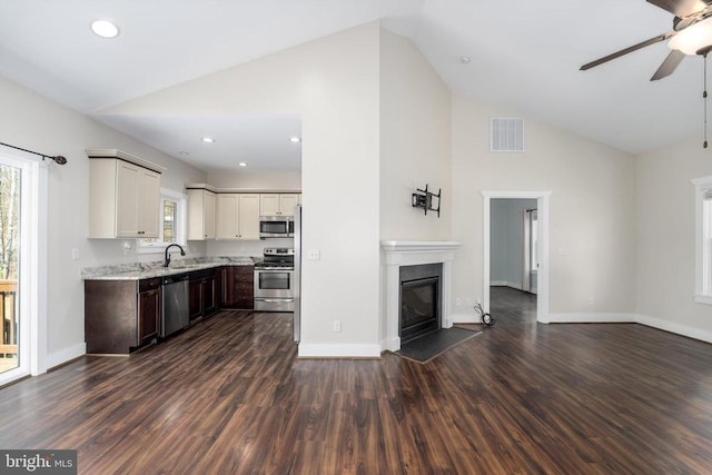 kitchen featuring visible vents, open floor plan, a fireplace with flush hearth, stainless steel appliances, and a sink