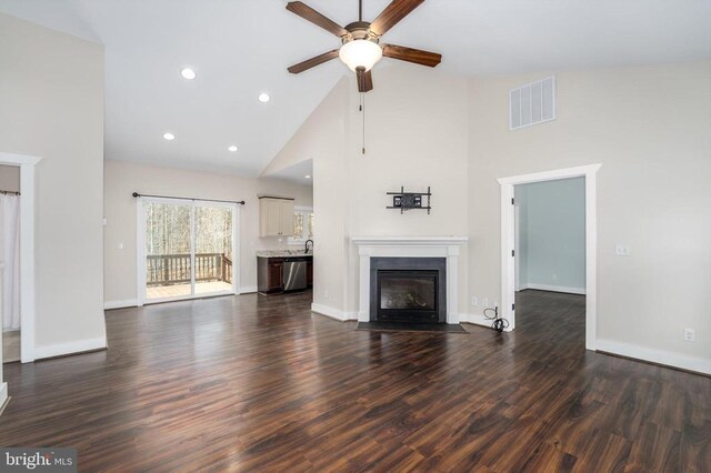 unfurnished living room with visible vents, a fireplace with flush hearth, a ceiling fan, dark wood-style floors, and baseboards