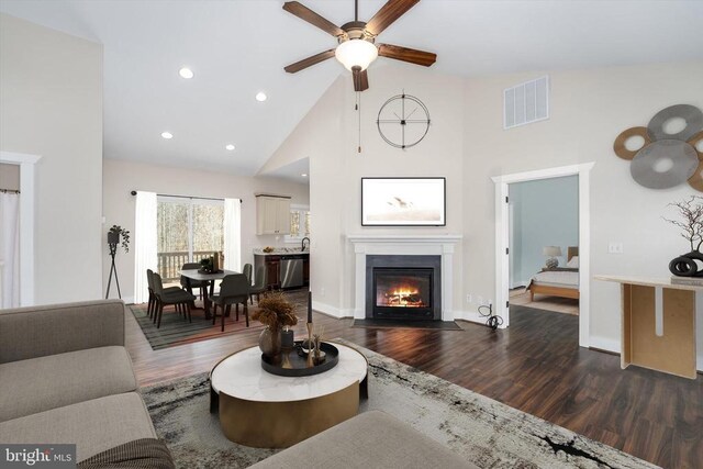 living area featuring visible vents, a fireplace with flush hearth, high vaulted ceiling, dark wood finished floors, and recessed lighting