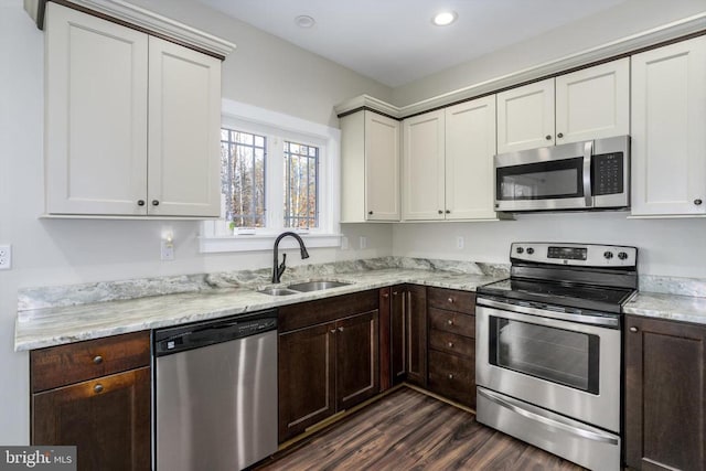 kitchen featuring dark wood finished floors, dark brown cabinets, appliances with stainless steel finishes, and a sink