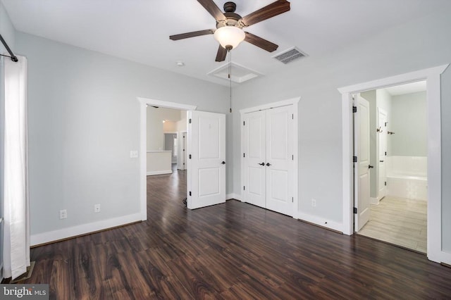 unfurnished bedroom with visible vents, attic access, baseboards, and wood finished floors