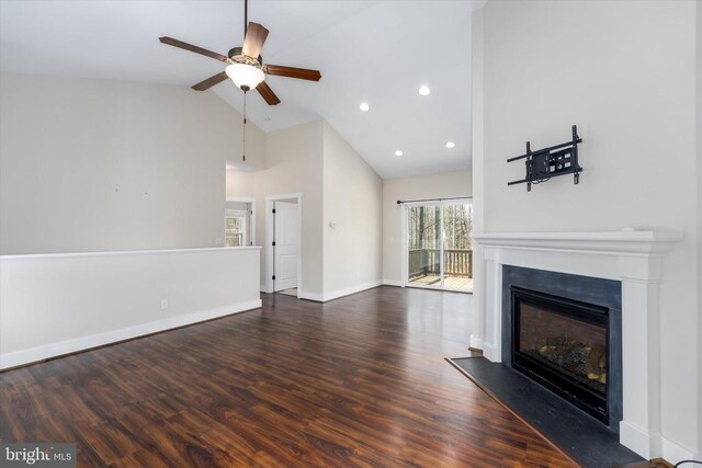 unfurnished living room featuring a fireplace with raised hearth, ceiling fan, baseboards, wood finished floors, and high vaulted ceiling