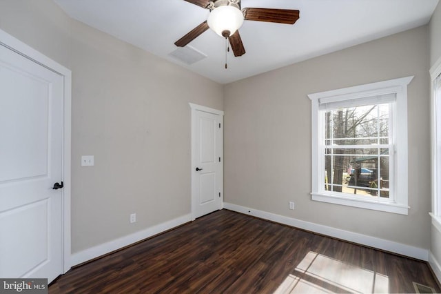 spare room featuring visible vents, a ceiling fan, baseboards, and dark wood-style flooring