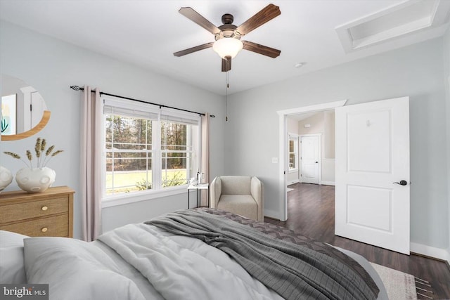 bedroom featuring attic access, wood finished floors, baseboards, and ceiling fan