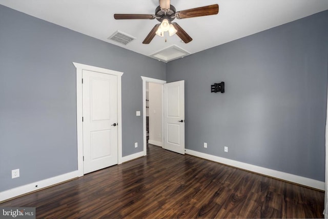 unfurnished bedroom featuring a ceiling fan, wood finished floors, visible vents, baseboards, and attic access