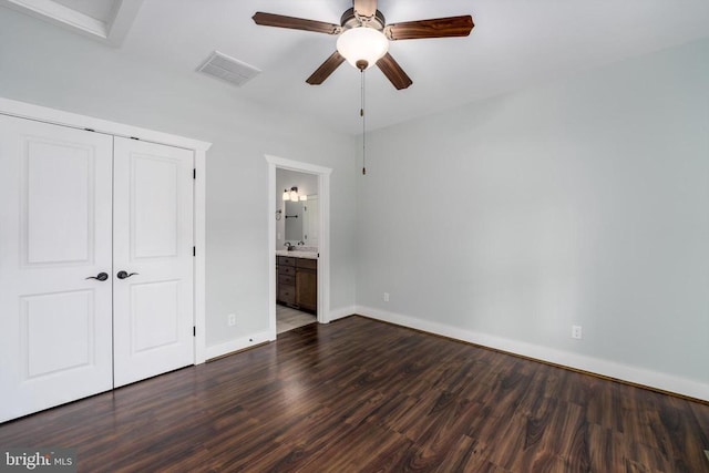 unfurnished bedroom featuring visible vents, a closet, connected bathroom, baseboards, and dark wood-style flooring