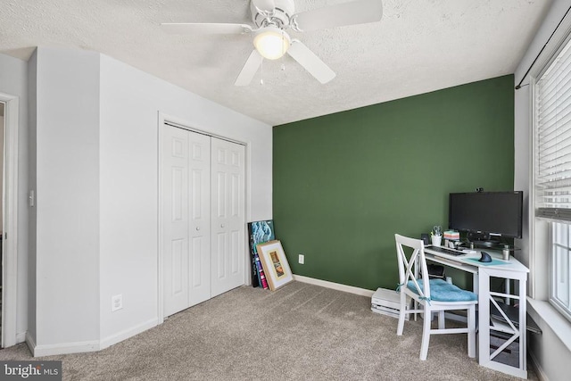 carpeted home office with a textured ceiling, ceiling fan, and baseboards