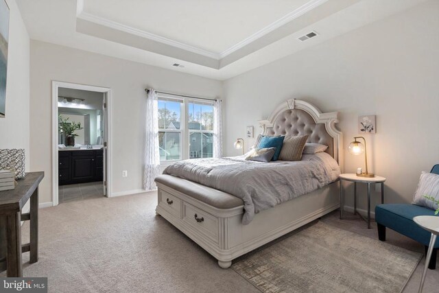 carpeted bedroom with crown molding, ensuite bathroom, and a raised ceiling