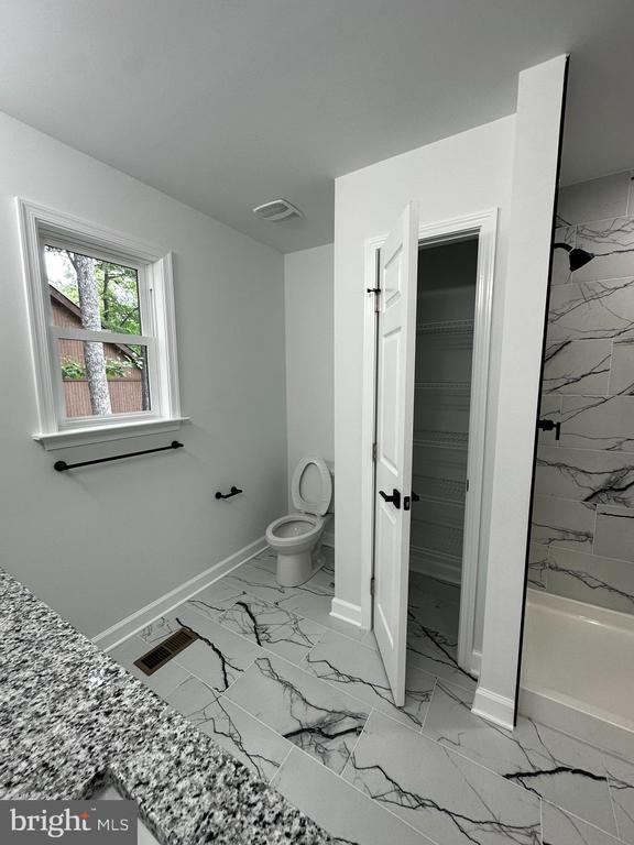 bathroom with tiled shower and toilet