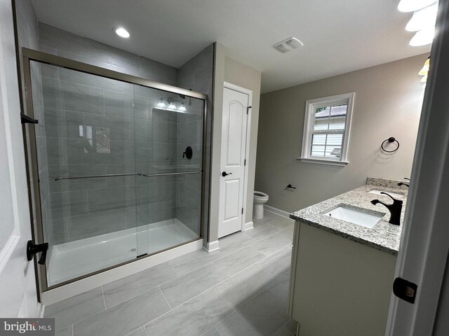 bathroom with vanity, a shower with shower door, and toilet