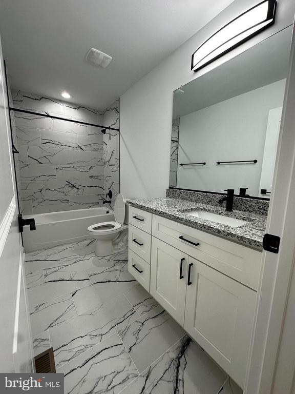 full bathroom with tiled shower / bath, vanity, and toilet